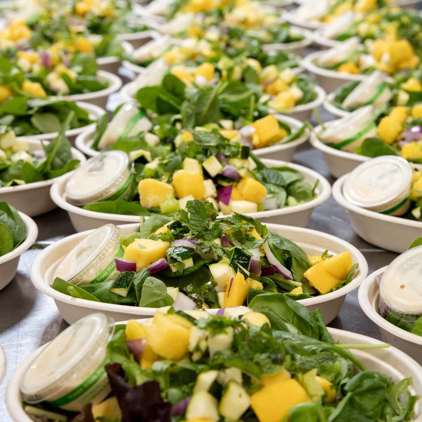 Fresh spinach, mango, and diced vegetables in bowls, ready for corporate catering.