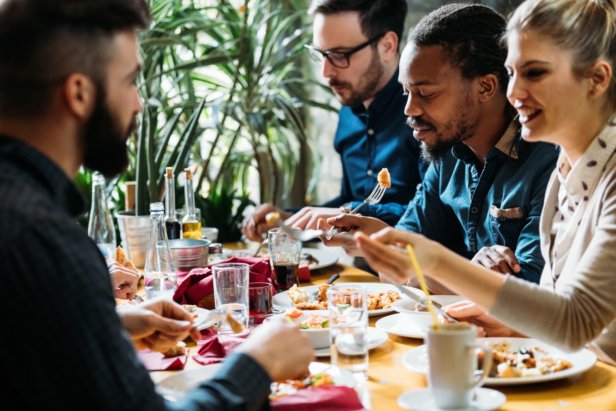 Colleagues enjoying a meal together at a lively table, a relaxed atmosphere, emphasizing corporate catering.