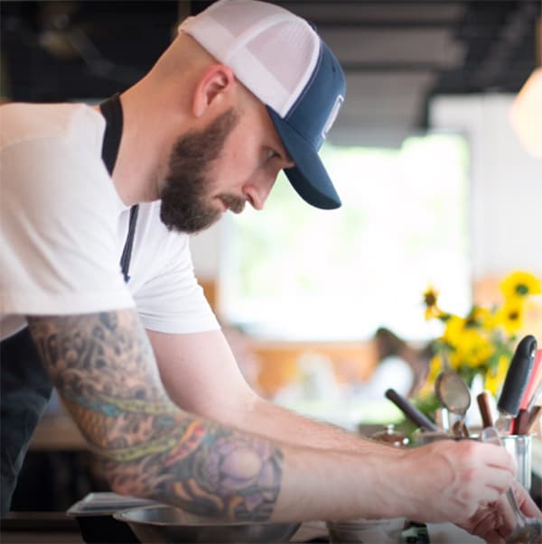 A chef prepares ingredients at a counter, showcasing a focus on quality for the corporate catering service.