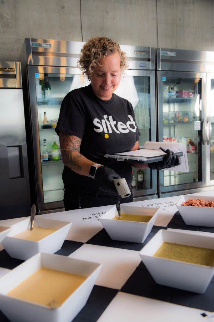 A Sifted caterer serves various soups at a corporate catering event.