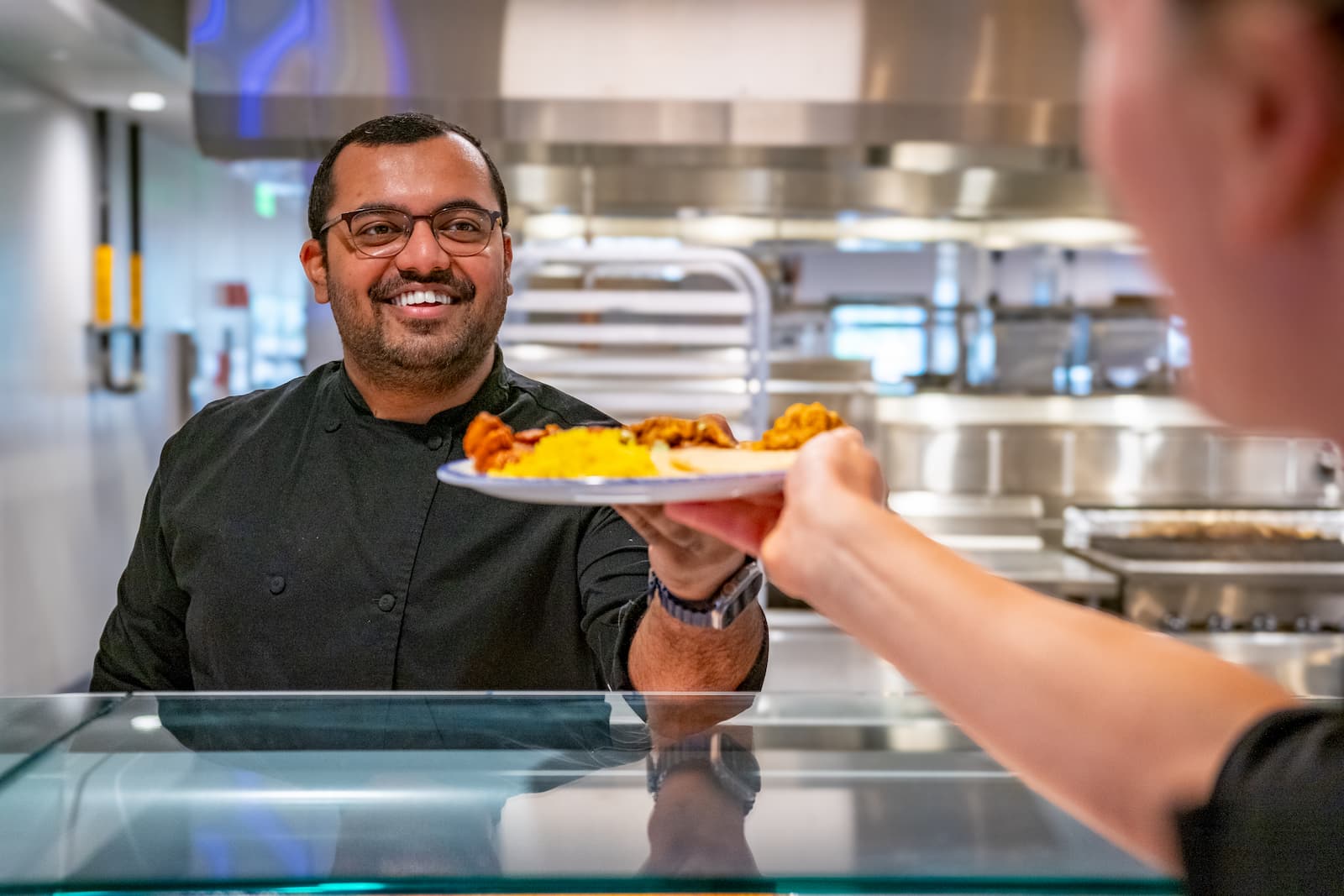 Chef hands a plate of food to a employee, highlighting a Corporate catering service.